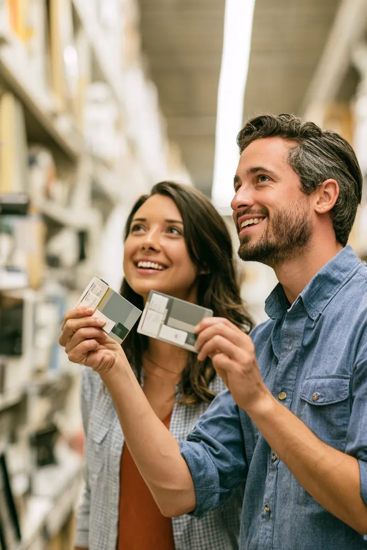 Couple comparing two paint swatch cards in a hardware store aisle
