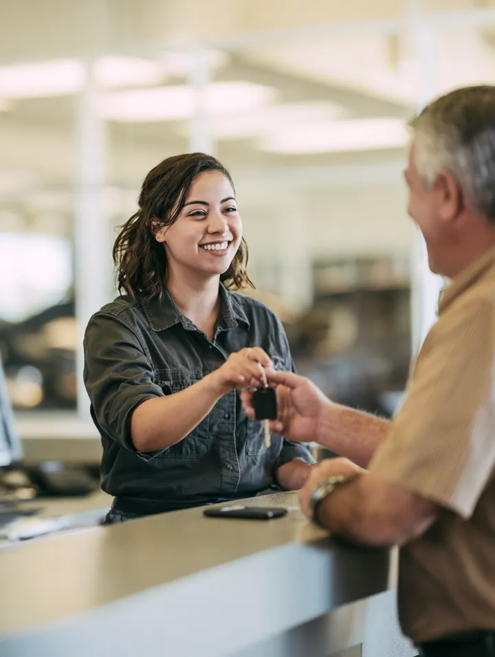 Mechanic handing car keys to a customer across a service counter