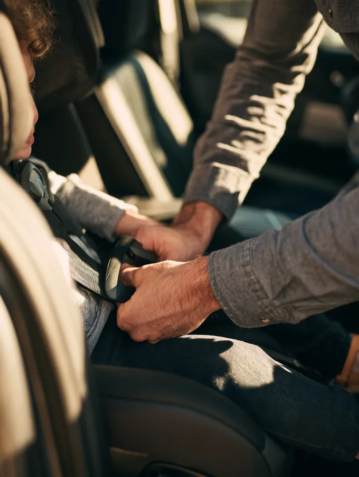 Parent buckling a child car seat in the back of a vehicle