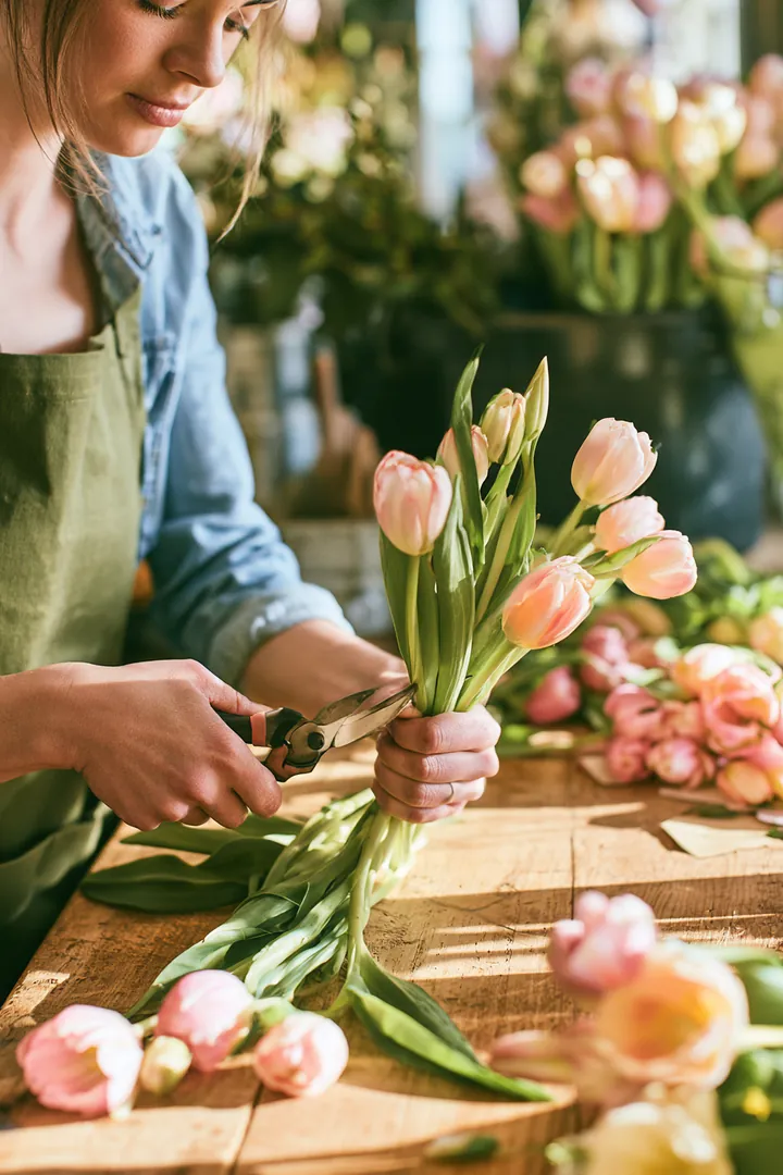 Florist trimming tulip stems at a flower shop workbench