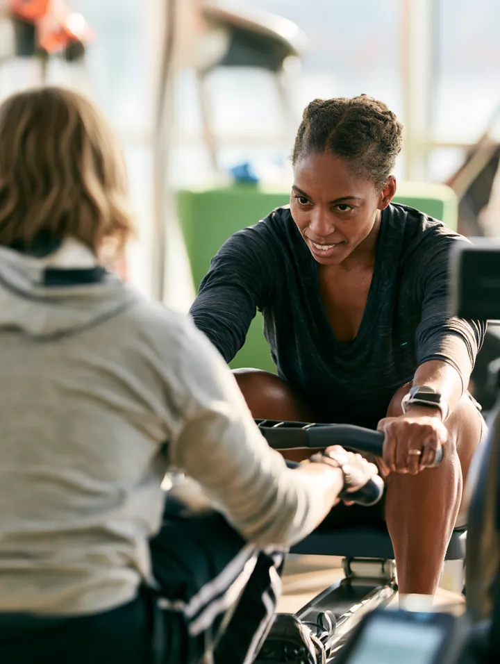 Personal trainer coaching a client on a rowing machine