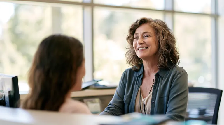 Receptionist greeting a visitor at a bright front desk